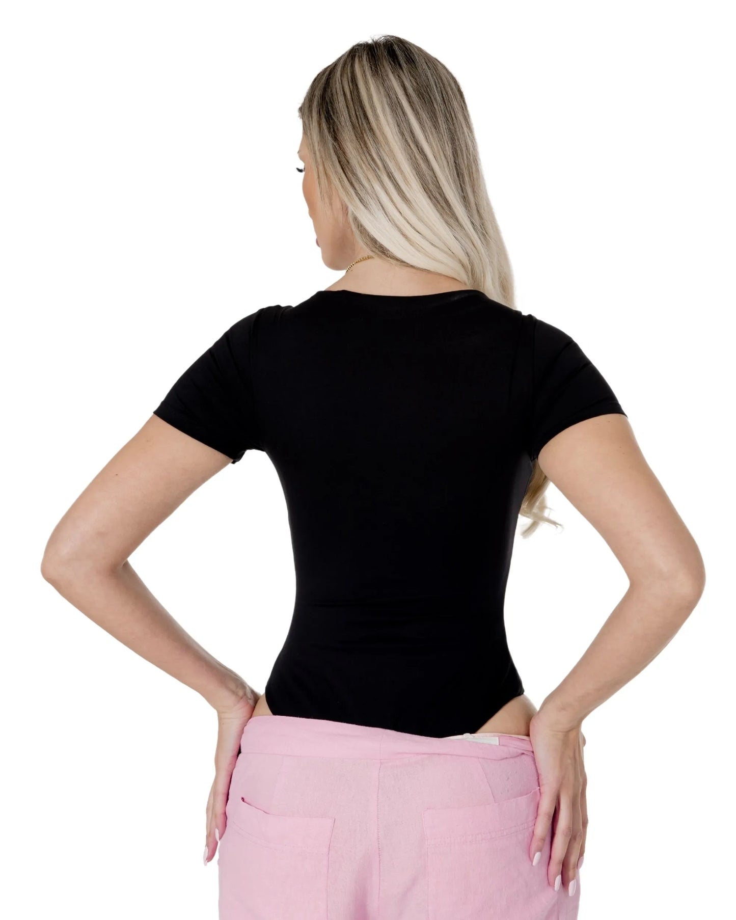 Woman wearing the Amara Top, showcasing the back view in black, styled with pink pants.