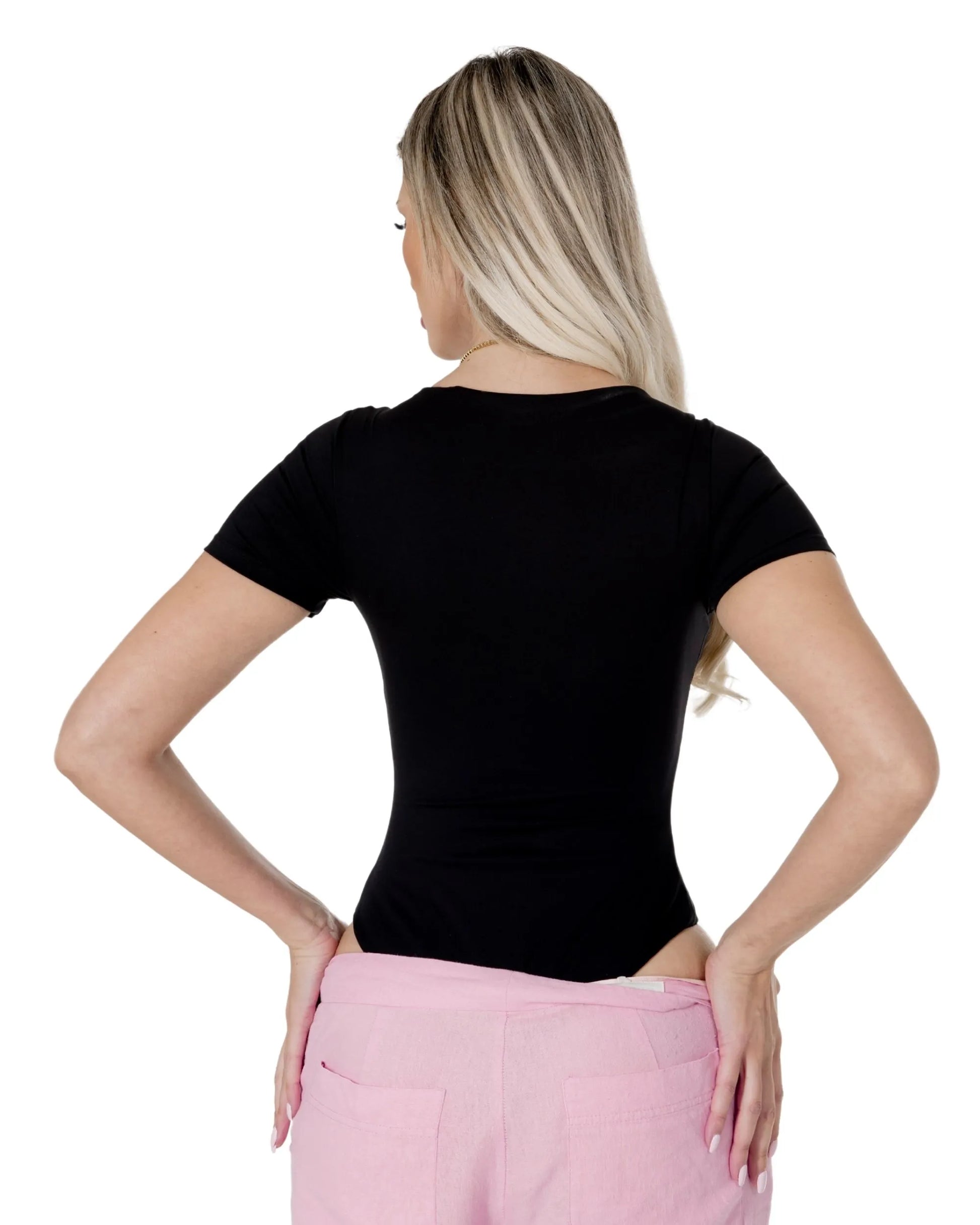 Woman wearing the Amara Top, showcasing the back view in black, styled with pink pants.