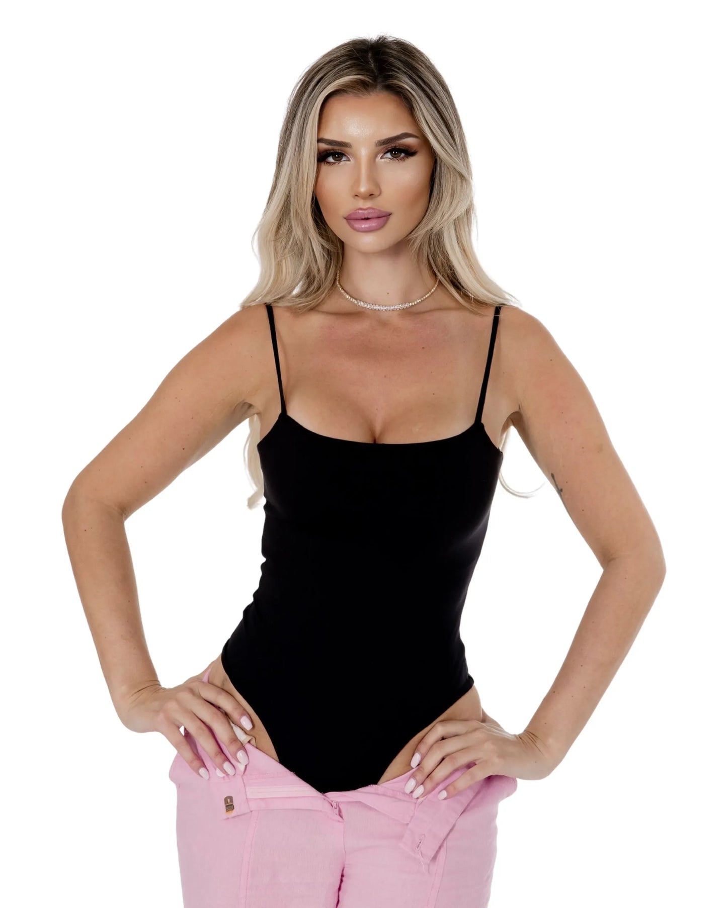 Model wearing the Elara Bodysuit in black with pink pants, showcasing a stylish and flattering fit.